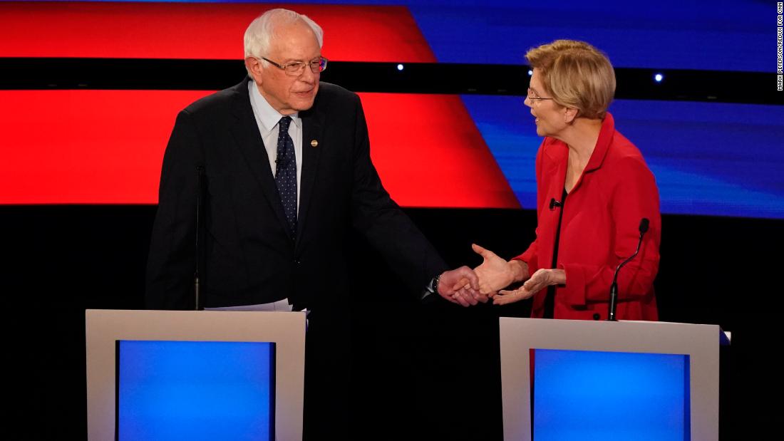 Sanders grabs the hand of US Sen. Elizabeth Warren during the Democratic debates in Detroit in July 2019.